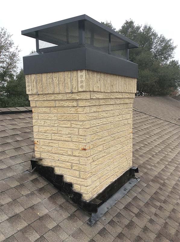Beige brick chimney with a metal chimney cap.